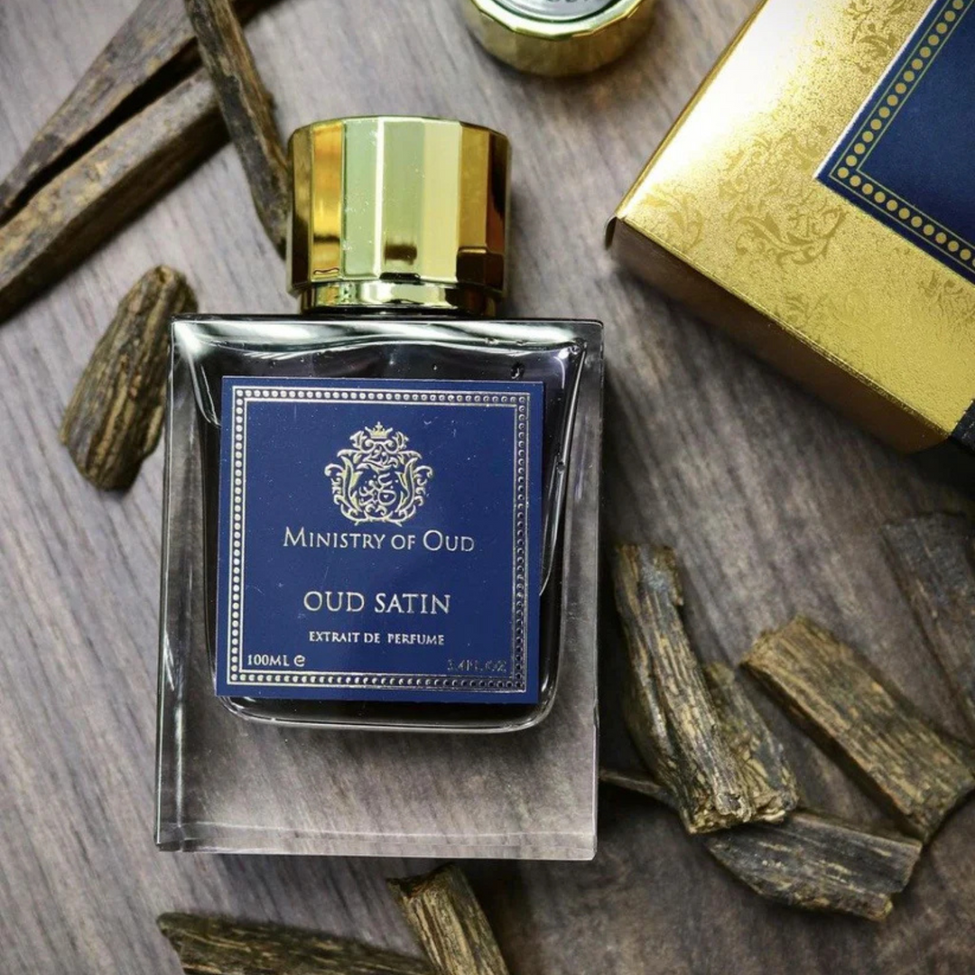 Paris Corner Oud Satin EDP 100ml perfume bottle on wooden table with wood pieces – rich warm floral oud fragrance with violet rose bergamot, Turkish rose oud benzoin, vanilla amber musk