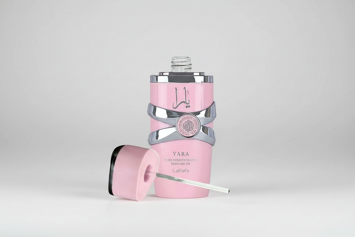Pink and silver bottle with a cap on a light gray background