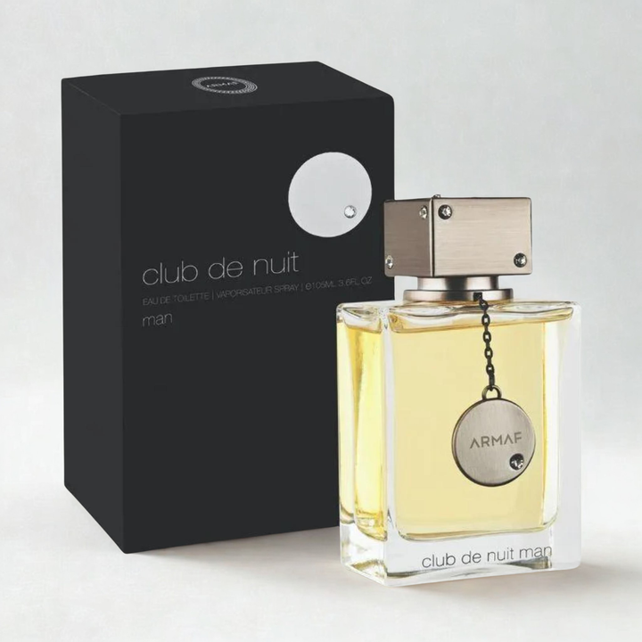 A bottle of ARMAF Club de Nuit Eau de Toilette with pale yellow liquid, shown next to its black packaging box on a light gray background.