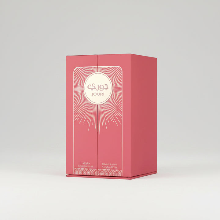 A pink rectangular perfume box for Jouri Lattafa, featuring a cream-colored circular logo with Arabic and English text, and gold sunburst line art on the front, set against a plain white background.