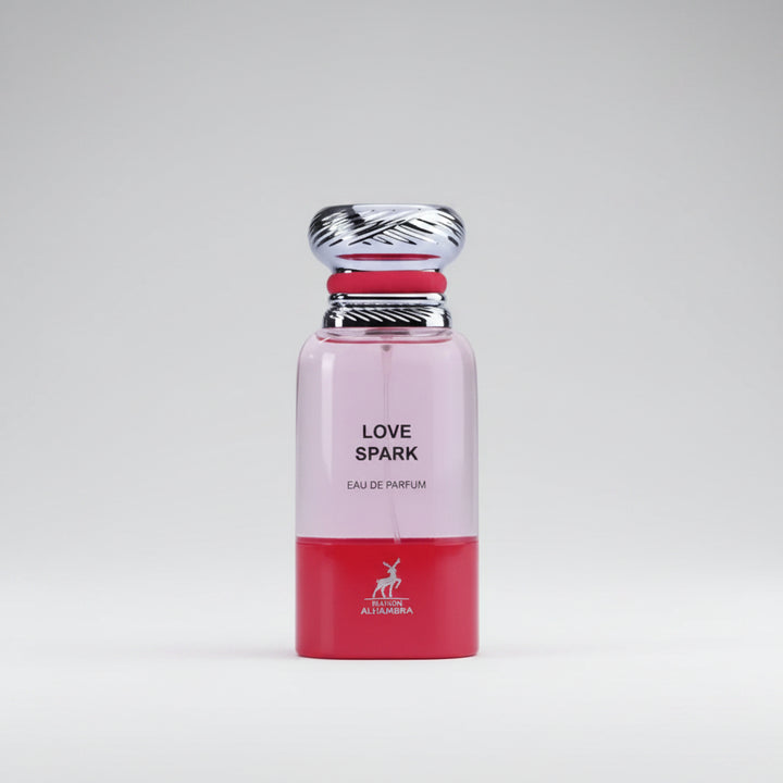 A perfume bottle labeled 'LOVE SPARK' with a pink upper half, red lower half, and a silver cap, set against a light gray background.